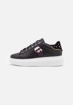 Sort læder sneaker med tyk hvid sål, karakter-logo på siden, juvelbesat hælkappe og sorte skosnører med mærke.