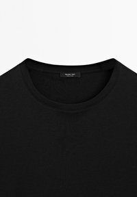 T-shirt nera a girocollo con maniche corte, che mostra il colletto e l'etichetta interna con la scritta "Massimo Dutti, Made in China."