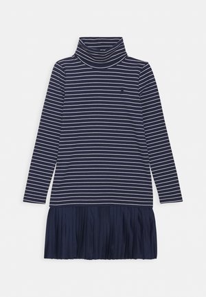 Robe bleu marine à manches longues avec des rayures blanches horizontales, col roulé et ourlet de jupe plissé.