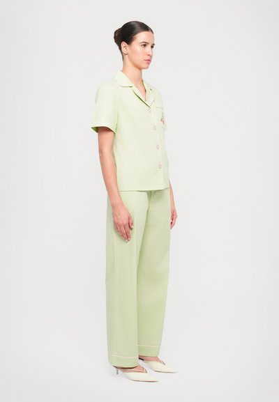 Light green short-sleeve shirt with buttons and pocket detail, paired with matching wide-leg trousers; features contrast piping and smooth fabric.