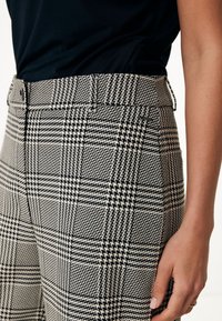 Karierte Hose mit einem schwarz-weißen Muster, hoher Taille, Gürtelschlaufen und tailliertem Schnitt. Glatte Textur und strukturiertes Design.