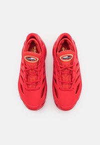 Par av ljusröda Adidas ClimaCool-sneakers med meshsidor och snören, sedd ovanifrån på en vit bakgrund.