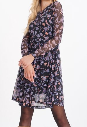 Czarna sukienka w kwiaty z długimi, przezroczystymi rękawami, zdobiona misternymi niebieskimi i różowymi wzorami, dopasowana w talii, z rozłożystą, sięgającą kolan spódnicą.
