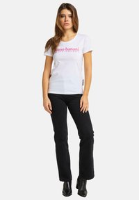 Hvid bomulds T-shirt med pink trykt tekst "bruno banani" og "IKKE TIL ALLE." Sæt sammen med sorte denimbukser og sorte ankelstøvler.