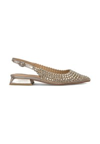 Chaussure slingback avec une finition dorée métallique, un bout pointu, embellie de clous en métal et un petit talon carré. Présente des bords festonnés.