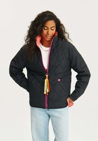 Prošívaná černá bunda s růžovou podšívkou, s předním zipem, bočními kapsami a barevným řetízkem na zip.