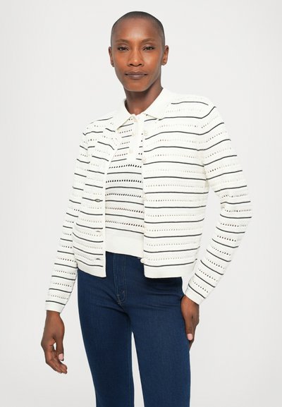 Witte gebreide cardigan met zwart gestreepte details en patronen, voorzien van een kraag en knopen aan de voorkant.