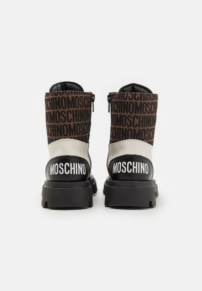 Bottes noires et beiges avec le motif du logo MOSCHINO, dotées d'un dessus en cuir lisse et en textile, d'une semelle noire surélevée et de détails zippés.