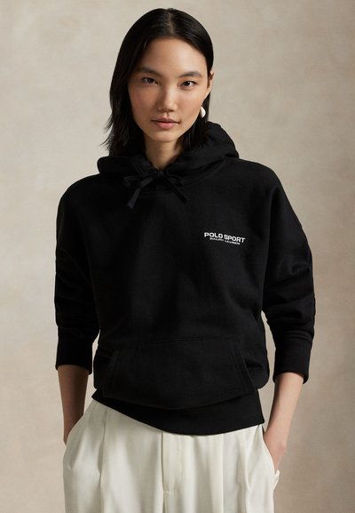 Juodas medvilninis džemperis su gaubtu ir priekiu kišene, reguliuojamu raišteliu gaubte ir baltu „POLO SPORT“ logotipu. Ypatingumas – gofruoti rankogaliai ir apačia.