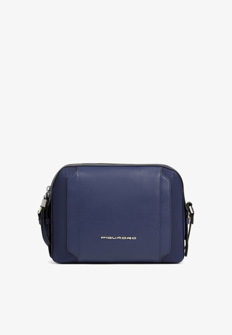 Bolso bandolera compacto de piel azul marino con logo plateado de Piquadro y correa ajustable sobre fondo blanco.