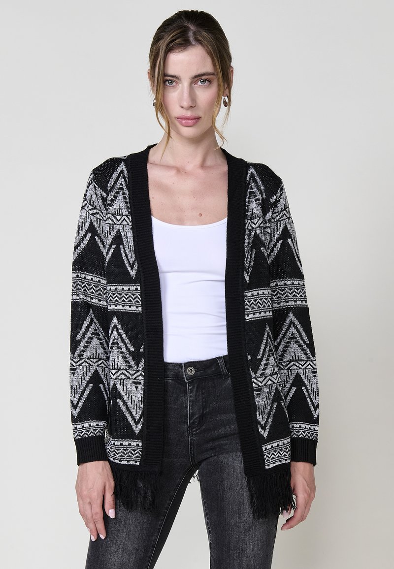 Cardigan lavorato a maglia in bianco e nero con motivi geometrici, apertura frontale, maniche lunghe e orlo frangiato. Tessuto texturizzato con colori a contrasto.
