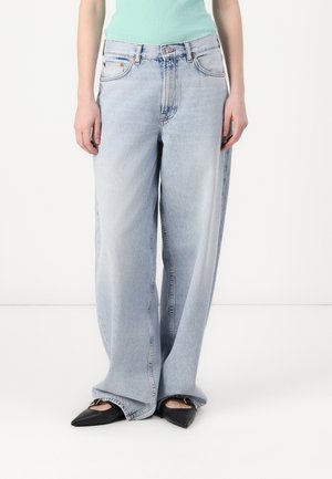 Jean à coupe large et délavé clair, taille haute. Confectionné en denim avec un léger effet délavé. Assorti à des chaussures noires pointues et un haut côtelé vert menthe.