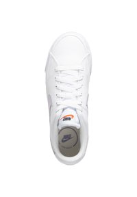 Valkoiset urheilukengät, joissa on teksturoitu päällinen, pyöreä kärki, litteät nauhat ja violetti Nike-logon swoosh. Ominaisuuksiin kuuluu pehmustettu pohja, jossa on brändäys.