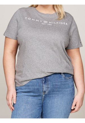 Grå bomulds T-shirt med korte ærmer, med hvid "TOMMY HILFIGER EST. 1985" tekst på fronten. Kombineret med blå denim jeans.