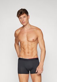 Donkergrijze boxershorts met een merk-elastische tailleband met rode en witte accenten. Strakke pasvorm met een gladde textuur.