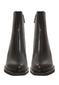 Botas de tobillo de cuero negro con un diseño elegante, cierre de cremallera en la parte posterior, textura suave y un acabado sutilmente brillante.