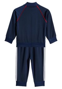 Mornarska trenirka iz gladkega blaga, z rdečimi detajli ob ramenskem delu in belimi bočnimi črtami na hlačah. Želeti manšete in ovratnik.