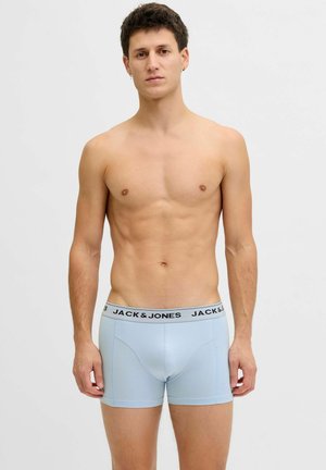 Young man standing, wearing light blue boxer briefs with "JACK & JONES" waistband, against a plain white background.