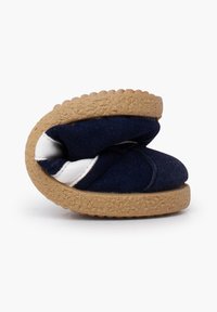 Navy blue slip-on shoe with a soft upper, featuring a white accent and a textured brown rubber sole. Folded design for compact storage.