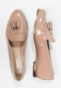 Mocassins en cuir verni nude avec talon plat, détails cousus et deux pampilles avec accents en métal argenté.