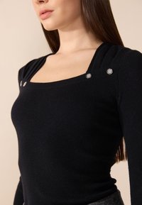 Czarny prążkowany longsleeve z kwadratowym dekoltem, dwoma ozdobnymi srebrnymi guzikami na ramionach oraz dopasowanym krojem.