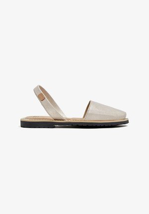 Sandalia slingback de color dorado metálico con punta redondeada, parte superior de cuero suave y suela exterior de goma negra con surcos sutiles para tracción.