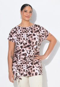 Lehký top s krátkým rukávem, který má růžový a hnědý leopardí vzor, boční rozparky a mašličku na lemu. Hladká textura látky.