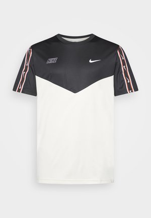 Camiseta de manga corta Nike en blanco y negro, con un diseño de chevron, textura suave y rayas rojas en las mangas.