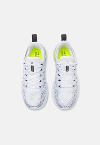 Baskets blanches à tige en mesh, avec des accents noirs et des semelles intérieures jaunes vives. Comprend des lacets et une languette à l'arrière pour un enfilage facile. Conception légère.