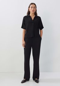 Zwart tweedelig ensemble met een kortärmelige overhemd met kraag en bijpassende broek. Zachte stof met een comfortabele pasvorm en een minimalistisch ontwerp.