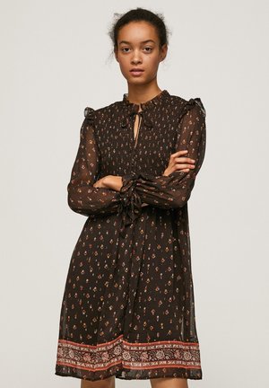 Schwarzes Kleid mit floralem Muster, durchscheinendem Stoff, Rüschenschößchen, Neckholder Detail und kontrastierender, gemusterter Saum. Mittellang und lockere Passform.