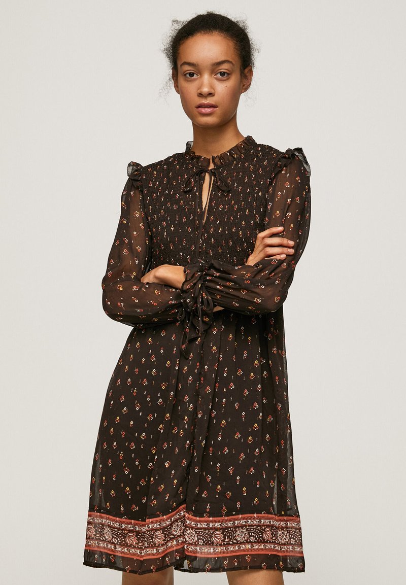 Rochie neagră cu model floral, material transparent, mâneci cu volane, detalii cu fundă la gât și fustă cu margine contrastantă. Lungime medie și croi lejer.