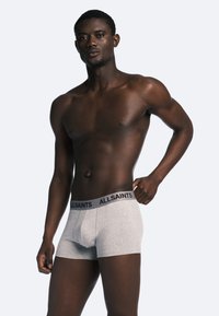 Des boxers en coton gris avec une ceinture noire portant la marque "ALLSAINTS", offrant une coupe ajustée avec une texture lisse et un design minimaliste.