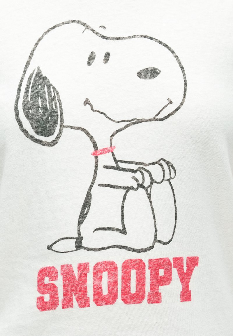 T-shirt blanc présentant un graphisme de Snoopy, un chien de dessin animé, dessiné en noir avec un collier rouge et le mot "SNOOPY" en lettres rouges en gras.