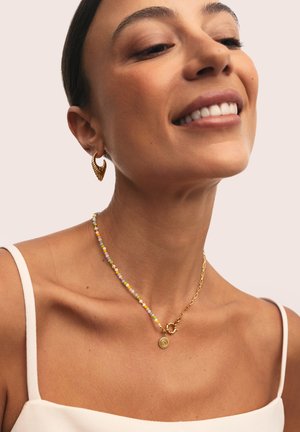 Gold-tone earrings and a beaded necklace featuring pastel-colored beads and a circular pendant detail; worn against bare skin.
