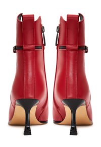 Bottes basses en cuir rouge au design élégant, avec un talon incurvé, une fermeture éclair arrière et des coutures détaillées sur les côtés.
