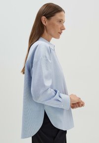Camicia azzurro chiaro a maniche lunghe con un sottile motivo a griglia, vestibilità rilassata, orlo arrotondato e polsini a contrasto.