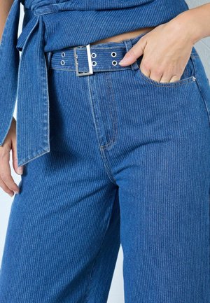 Blue vertical striped denim pants feature a silver buckle belt, side pocket, and relaxed fit, showcasing a textured surface and tailored design.