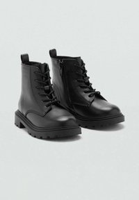 Botas de tobillo de piel negra con punta redondeada, cordones en la parte delantera, cremallera lateral y suela gruesa con dibujo. Textura suave con un detalle mínimo.