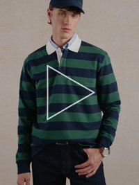 Žalia ir tamsiai mėlyna dryžuota ilgomis rankovėmis polo marškinėliai su baltais apykaklėmis, derinami su tamsiomis džinsais ir riešo laikrodžiu. Minimalistinis dizainas, laisvo silueto.