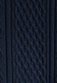 Granatowy, pleciony materiał z wyraźnym wzorem w warkocze, zawierający elementy diagonalne i pionowe, ukazujący grube i cienkie włókna.