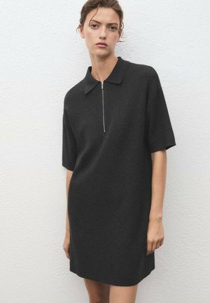 Abito nero realizzato in morbido tessuto, con colletto classico, maniche corte e dettagli con zip frontale. Design minimalista e silhouette snella.
