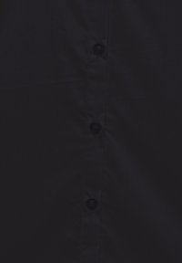 Tengerészkék gombos ing sima textúrával, öt fekete gombbal és klasszikus gallér kialakítással. Egyszerű és funkcionális.