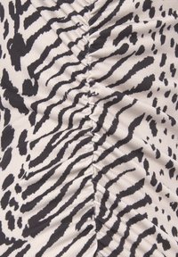 Čiernobiela látka s potlačou zvieracieho vzoru s nariadeným designom. Mäkká textúra, výrazné pruhy a škvrny na svetlom béžovom pozadí.