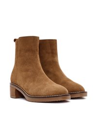 Stivaletti alla caviglia in suede beige con una finitura liscia, punta arrotondata e tacco quadrato. I dettagli delle cuciture lungo la suola arricchiscono il design.