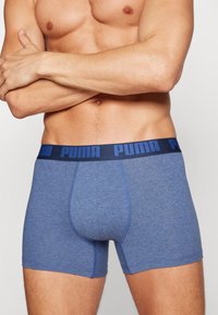 Boxeri scurți Puma, de culoare albastră, cu un tiv navy pe care este inscripționat numele brandului. Material moale și elastic, cu o croială strânsă, de tip athletic.