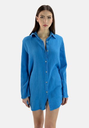 Klar blå button-up skjorte, lavet af tekstureret stof med en krøllet overflade, der har krave og lange ærmer.