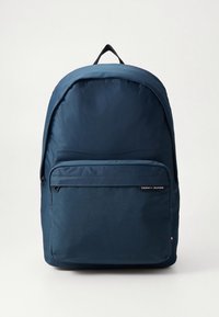 Nirnavotas zilas mugursoma no izturīga auduma, ar priekšējā rāvējslēdzēja kabatu, apaļu formu un augšējo rokturi ērtai nēsāšanai.