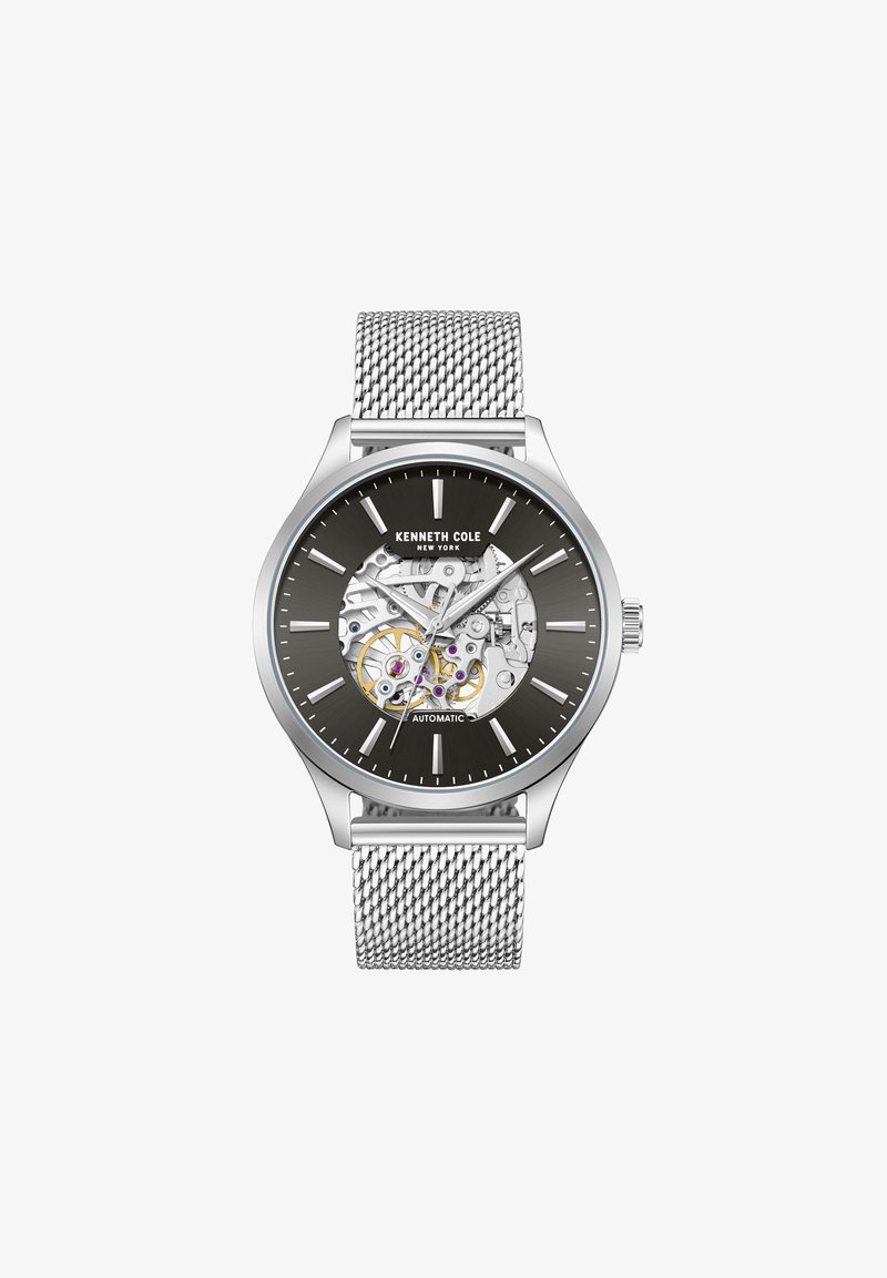 Sudraba automātiskās pulksteņi ar tīkla siksnu, melnu ciparnīcu, caurspīdīgu aizmuguri un sudraba stundu rādītājiem. Iekšējās mehānikas ir sarežģītas.