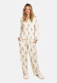 Lightweight, cream-colored pajama set featuring floral patterns in orange and blue. Long-sleeve shirt with pockets, matching loose-fit pants, and fluffy slippers.